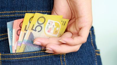 Woman saving money placing it in her back pocket.