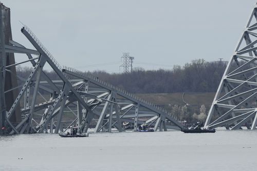 Boats move near a container ship as it rests against wreckage of the Francis Scott Key Bridge on Tuesday, March 26, 2024, as seen from Dundalk, Md. 