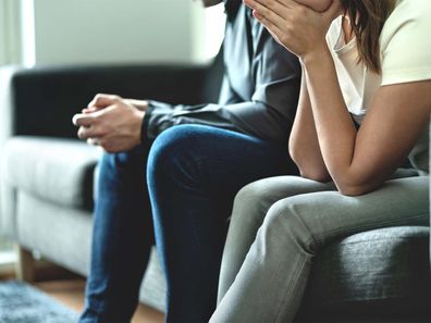 Man and woman sitting on a couch tired from fighting