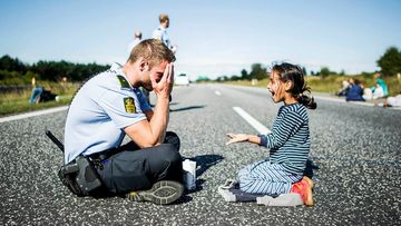 A Danish police officer plays with a young Syrian refugee girl. (Michael Drost-Hansen, via Reddit)