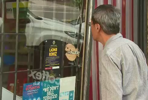'Sean' Wang looks into his shop after the overnight shooting. (9NEWS)