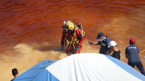 A police diver searches for a suitcase with a fifth body at the Red Lake in Mitsero village, Cyprus.