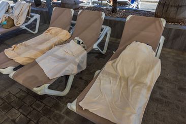 Close-up view of sun loungers with wet towels near outdoor pool in hotel. Spain.