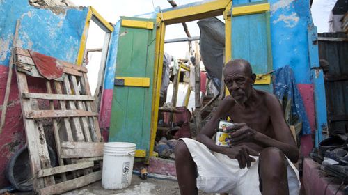 Jean Claude Dimanche in front of his ruined home. (AP)