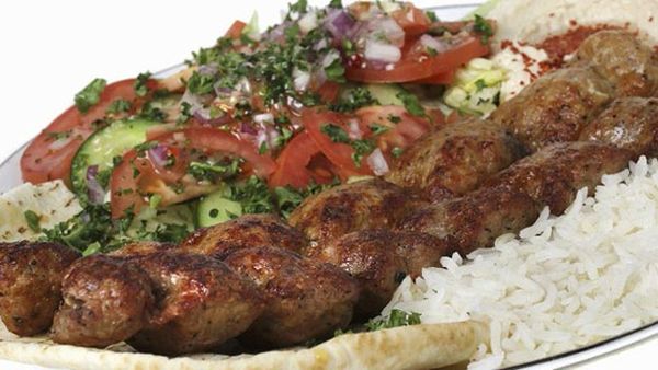 Lula kebab on rice with tomato and cucumber salad