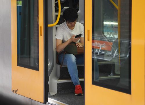 A commuter sits on the steps of a Sydney Trains carriage during rush hour at Strathfield train station. (AAP)