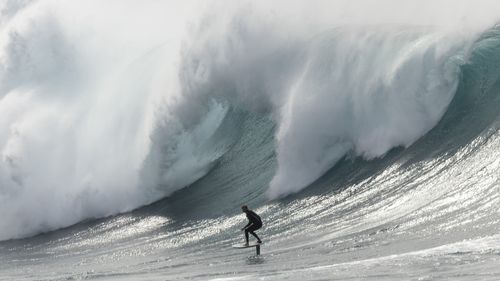 A surfer rides on a large wave breaking off Wedding Cake Island on March 28, 2026 in Sydney, Australia