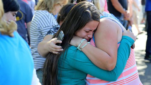 A woman is comforted as friends and family wait for students at the college. (AAP)