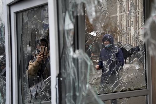 A man takes a photo of windows of a police kiosk damaged by demonstrators during a protest in Almaty, Kazakhstan, Wednesday, Jan. 5, 2022. 