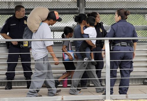 Ever Castillo (left) voluntarily returns across the Mexican border with his family after being told they would be separated. Picture: AAP