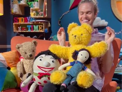 TikTok creator Mr. Luke sitting on a couch with Play School toys.
