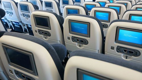 rows of seats on plane with entertainment screens