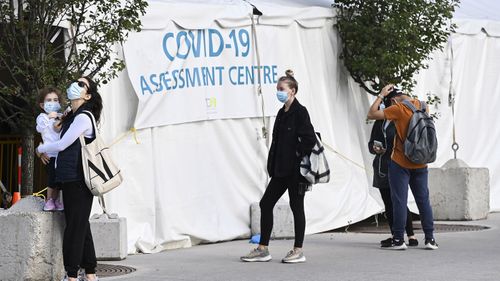 People wait in line at a COVID-19 assessment centre at Women's College Hospital during the coronavirus pandemic in Toronto.