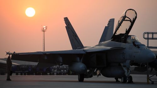 A pilot makes final checks on a Royal Australian Air Force F/A-18F Super Hornet prior to a mission at the main air operating base, in the Middle East region. (AAP)