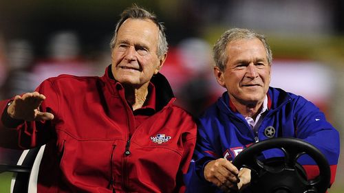 Former US Presidents George H.W. Bush (L) and his son George W. Bush (R) arriving on a cart to throw out the ceremonial first pitch before game four of the 2010 World Series at Rangers Ballpark in Arlington,Texas.