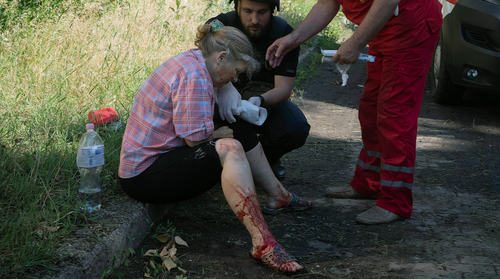A police officer and paramedic give the first aid to a woman wounded by the Russian shelling in city center in Slavyansk, Donetsk region, Ukraine, Monday, June 27, 2022. 