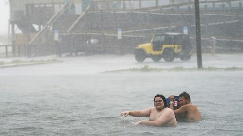 Two men play in hurricane floodwaters in Pensacola, Florida. Authorities warn not to do this.