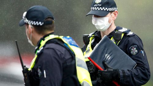 A member of Victoria Police performs an I.D. check at the entrance to the Flemington Towers Government Housing complex 