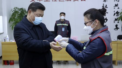 Chinese President Xi Jinping, left, wearing a protective face mask receives a temperature check.