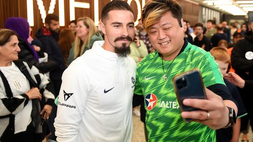 Jamie Maclaren of the Socceroos meets a fan at Melbourne Airport.
