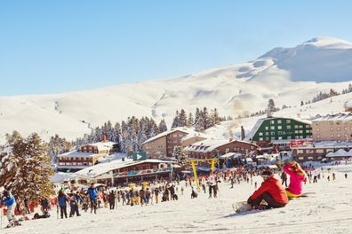 Skiing and snowboarding in Turkish  winter resort Uludag. Uludag, Bursa, Turkey - January 21, 2017 : Skiers and snowboarders on a wide slope of Uludag ski resort. Uludag is the most popular winter sports center in Turkey.