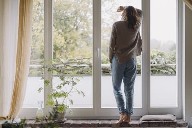 Woman standing at window at home