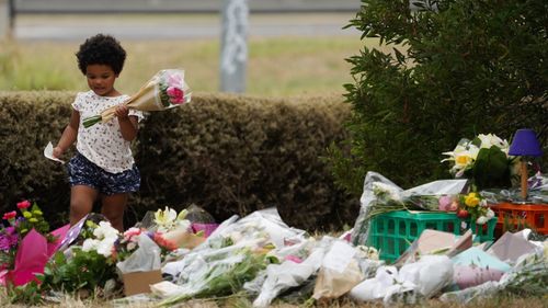 A young girl leaves flowers at the growing memorial for Ms Maasarwe in Bundoora.