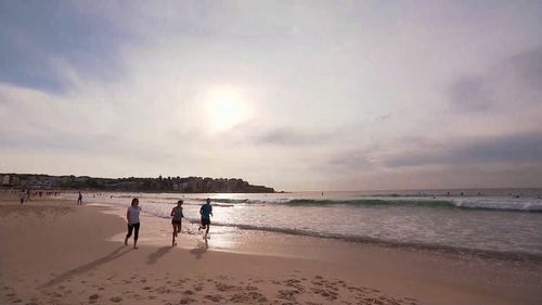 Beach walkers make the most of early temperatures before the mercury rises in Bondi.