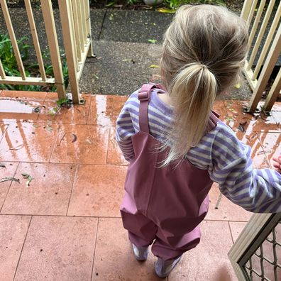 Toddler wearing water-repellent overalls from Kmart, junior unicorn rain boots