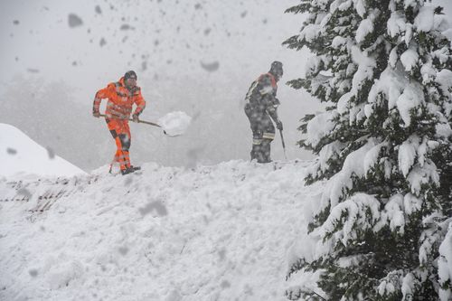 Men remove snow from the roof of a building in Elisabethszell, Germany.