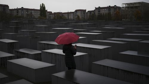 A woman with a red umbrella visits the Memorial for the murdered Jews of Europe, the so called Holocaust Memorial in central Berlin. 
