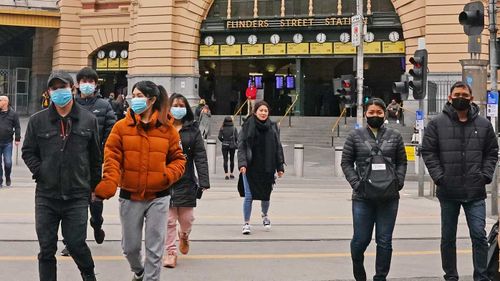 People in face masks outside Flinders Street Station in Melbourne.