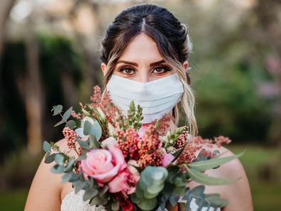 Bride holding flowers and wearing coronavirus mask.