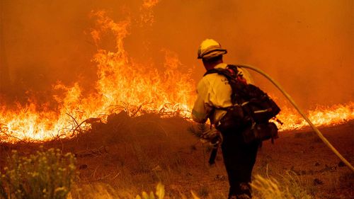 A firefighter battles the Caldor Fire along Highway 89 in California.