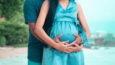 Young parents expecting new baby holding mother's belly in both hands front close up photograph under natural lights in the beach of Galle.