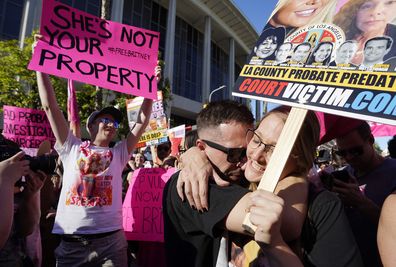 Britney Spears supporters Aaron Morris, second from right, and Elizabeth Crocker embrace outside a hearing concerning the pop singers conservatorship at the Stanley Mosk Courthouse, Friday, Nov. 12, 2021, in Los Angeles. A Los Angeles judge on Friday ended the conservatorship that has controlled Britney Spears life and money for nearly 14 years. (AP Photo/Chris Pizzello)