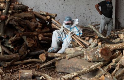 A family member carries wood to prepares funeral pyres for their relative who died from COVID-19 before cremation at Ghazipur cremation ground in New Delhi. 