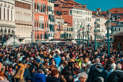 VENICE, ITALY - FEBRUARY 18, 2017: Crowds of tourists walking by typical venetian buildings near San Marco Square during famous  traditional carnival taking place each year in Venice, Italy.