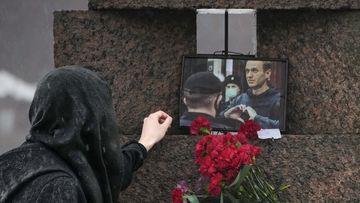 A woman touches a photo of Alexei Navalny after laying flowers paying the last respect to him at the Memorial to Victims of Political Repression in St. Petersburg, Russia on Saturday, Feb. 17, 2024