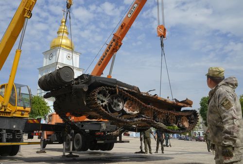 Ukrainian soldiers unload a destroyed Russian tank to install it as a symbol of war in central Kyiv, Ukraine, Friday, May 20, 2022. St Michael cathedral is in the background.(AP Photo/Efrem Lukatsky)