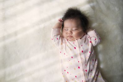Newborn baby sleeping on a white carpet