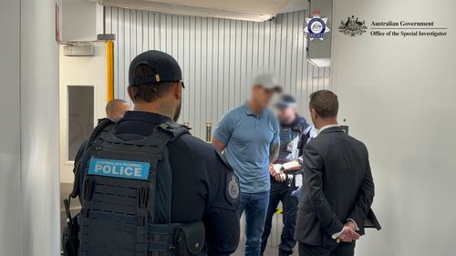 Le immagini fornite dalla polizia federale australiana mostrano Roberts-Smith ammanettato all'interno di un ponte aereo all'aeroporto di Sydney.