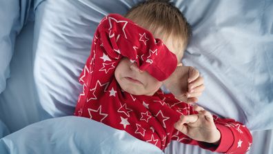 boy lying in bed in red pyjamas 