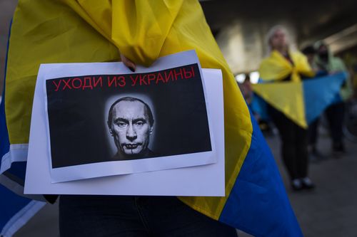 FILE - A demonstrator holds a banner depicting Russian President Vladimir Putin during a pro-Ukraine protest outside the Russian Embassy, after Russian troops have launched their anticipated attack on Ukraine, in Tel Aviv, Israel, Thursday, Feb. 24, 2022. Sign in Russian reads "get out of Ukraine". (AP Photo/Oded Balilty, File)