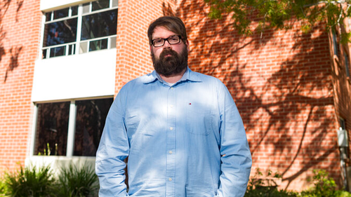 Chris Lambert, a musician and recording engineer stands in front of Muir Hall dormitory at California Polytechnic University. 