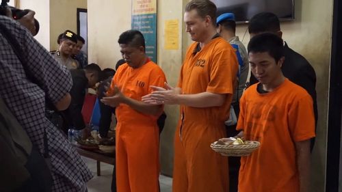 Van Iersel even managed to crack a smile as he was served his meal at Denpasar police station, where the pair is being held in the lead up to their court case.