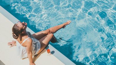 Fashionable woman sitting by the pool on the empty deck of a cruise liner. 