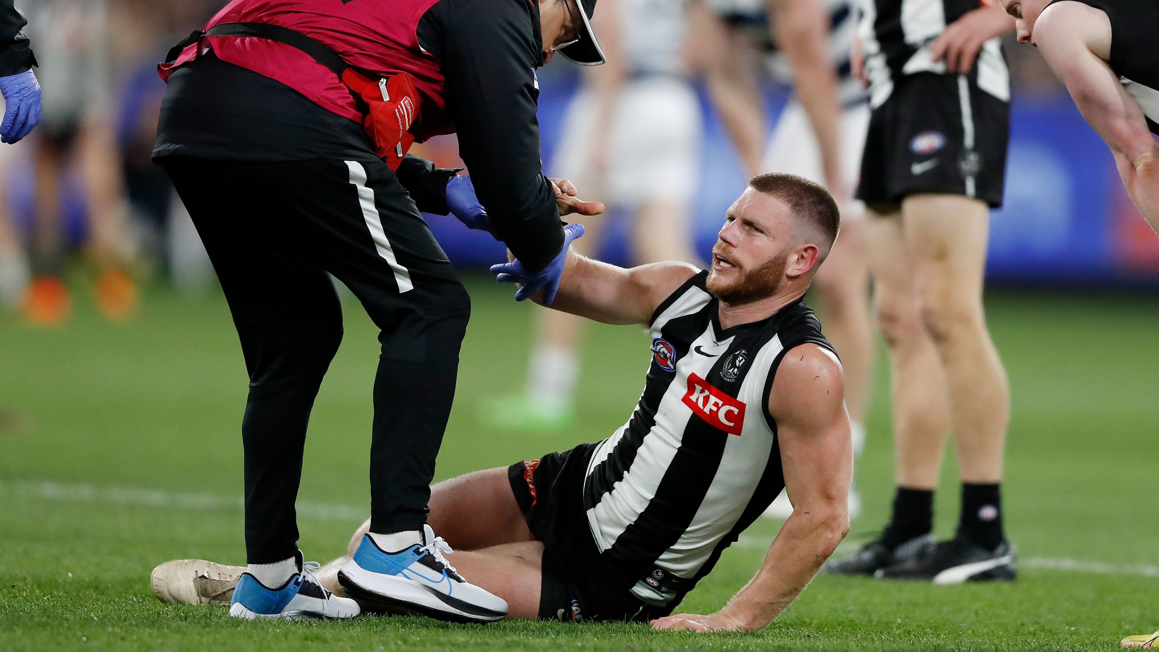 Taylor Adams of the Magpies is seen being assisted off the ground by medical staff during their qualifying final.