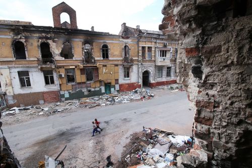 Дети идут между зданиями, разрушенными во время боев в Мариуполе, при правительстве Донецкой Народной Республики, на востоке Украины, среда, 25 мая 2022 года.
