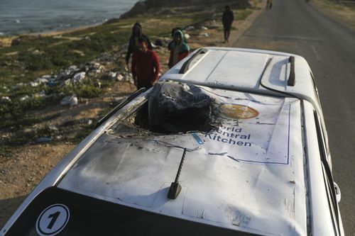 Palestinians inspect a vehicle with the logo of the World Central Kitchen wrecked by an Israeli airstrike in Deir al Balah, Gaza Strip, Tuesday, April 2, 2024.